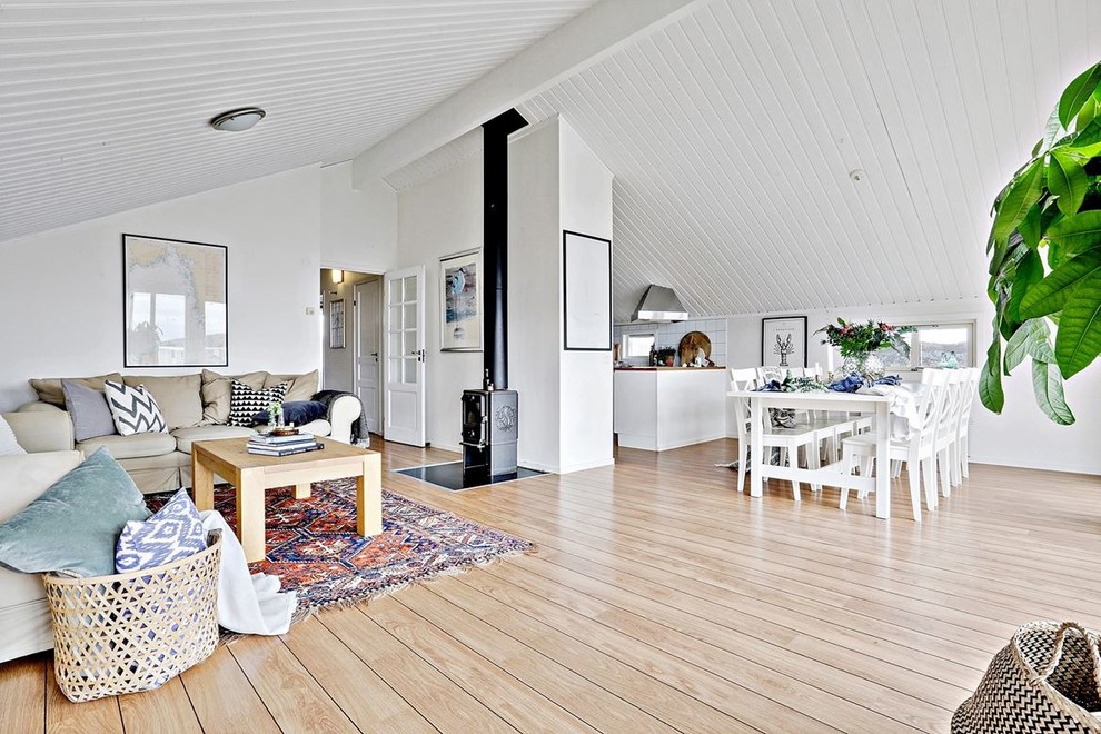Ejemplo de salón abierto campestre con paredes blancas, suelo de madera clara, estufa de leña, marco de chimenea de metal y suelo beige