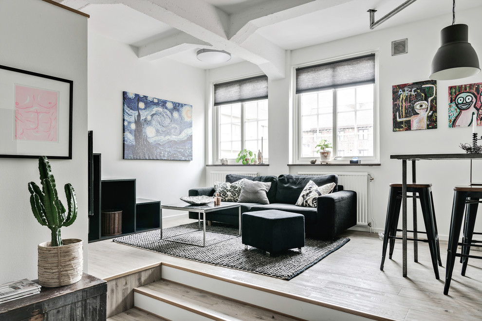 This is an example of a small industrial open plan living room in Gothenburg with white walls and light hardwood flooring.