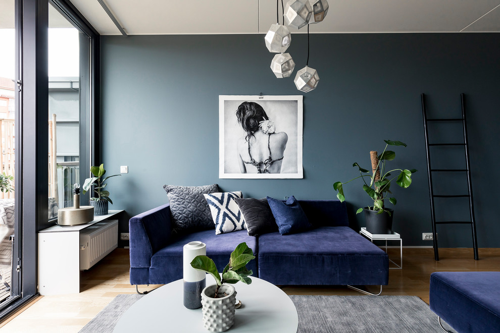 Photo of a medium sized contemporary enclosed living room feature wall in Stockholm with blue walls and medium hardwood flooring.