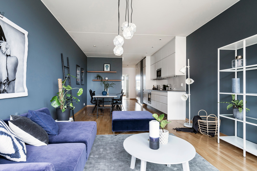 Offenes Modernes Wohnzimmer ohne Kamin mit blauer Wandfarbe und braunem Holzboden in Stockholm