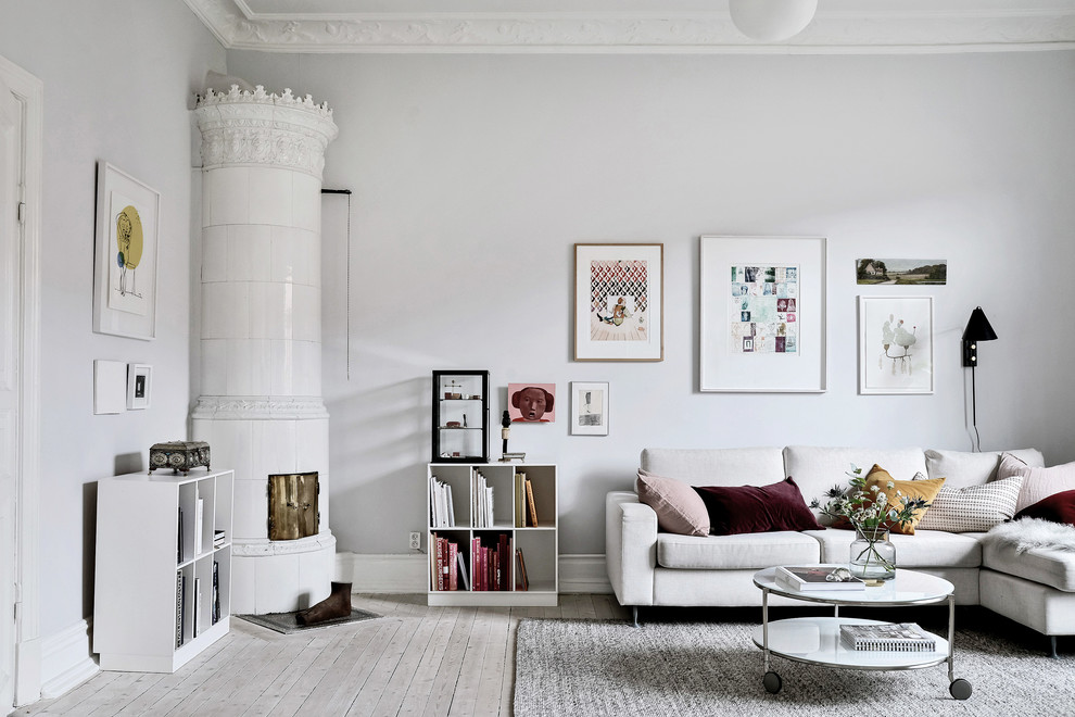 Mittelgroßes, Abgetrenntes Klassisches Wohnzimmer mit hellem Holzboden, Kaminofen, gefliester Kaminumrandung, grauer Wandfarbe und beigem Boden in Göteborg