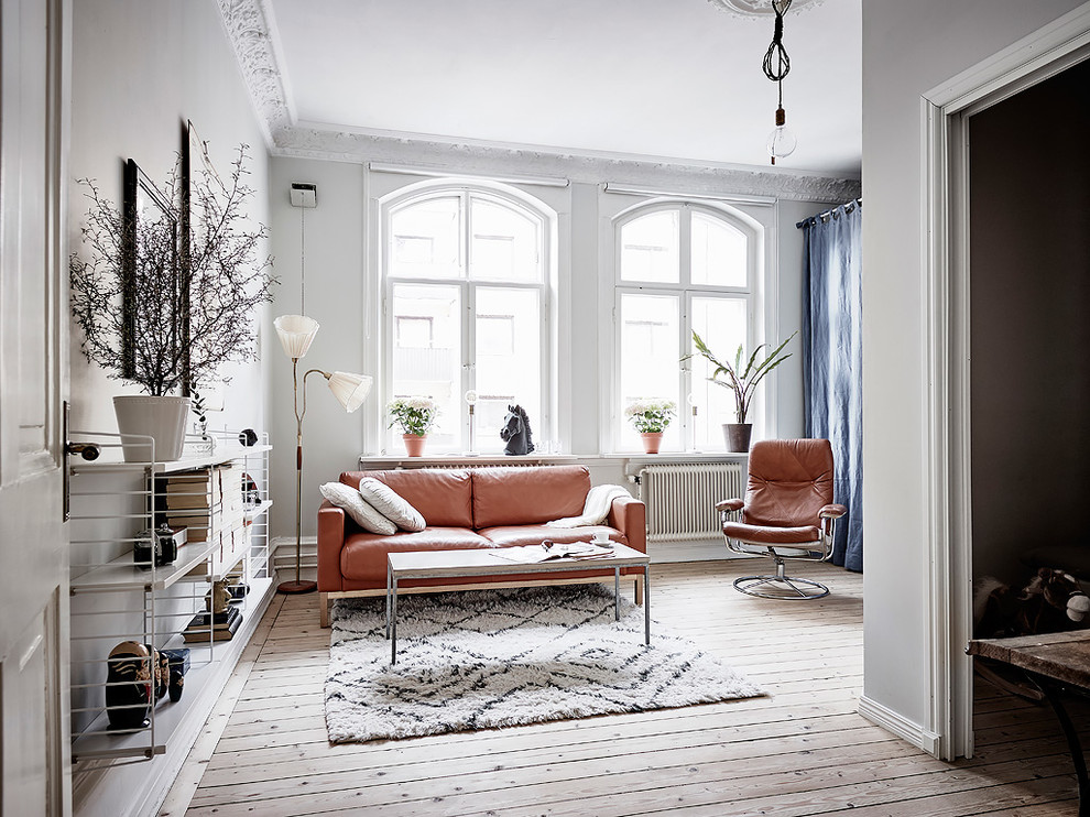 This is an example of a scandinavian living room in Gothenburg with white walls, light hardwood flooring and beige floors.