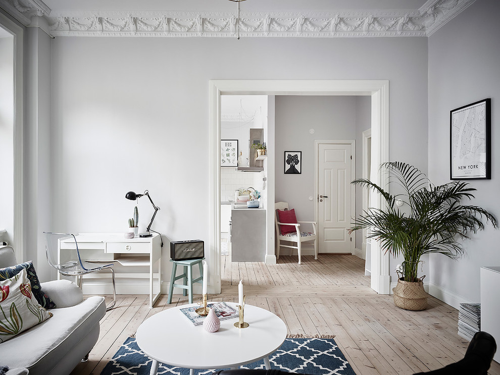 Minimalistisk inredning av ett vardagsrum, med grå väggar, ljust trägolv och beiget golv