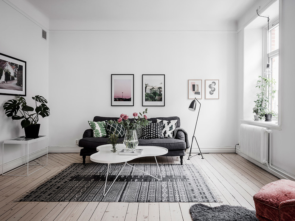 Nordisk inredning av ett mellanstort vardagsrum, med vita väggar och ljust trägolv