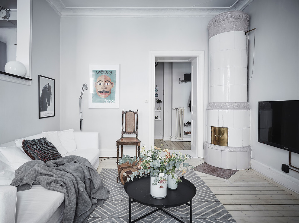 Inspiration pour un salon gris et blanc nordique fermé avec un mur blanc, parquet clair, une cheminée d'angle, un manteau de cheminée en métal, un téléviseur fixé au mur et un sol beige.