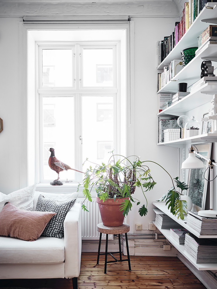 Nordisches Wohnzimmer mit weißer Wandfarbe, braunem Holzboden und braunem Boden in Göteborg