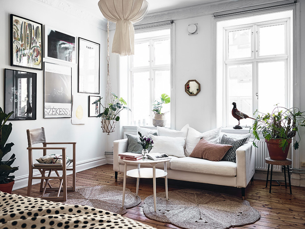 Skandinavisches Wohnzimmer mit weißer Wandfarbe, dunklem Holzboden und braunem Boden in Göteborg
