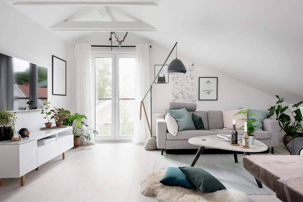 Inredning av ett minimalistiskt mellanstort loftrum, med vita väggar, ljust trägolv och en väggmonterad TV