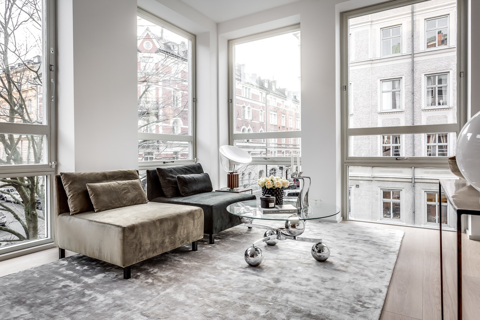 This is an example of a medium sized contemporary living room in Stockholm with white walls, light hardwood flooring, no fireplace and beige floors.