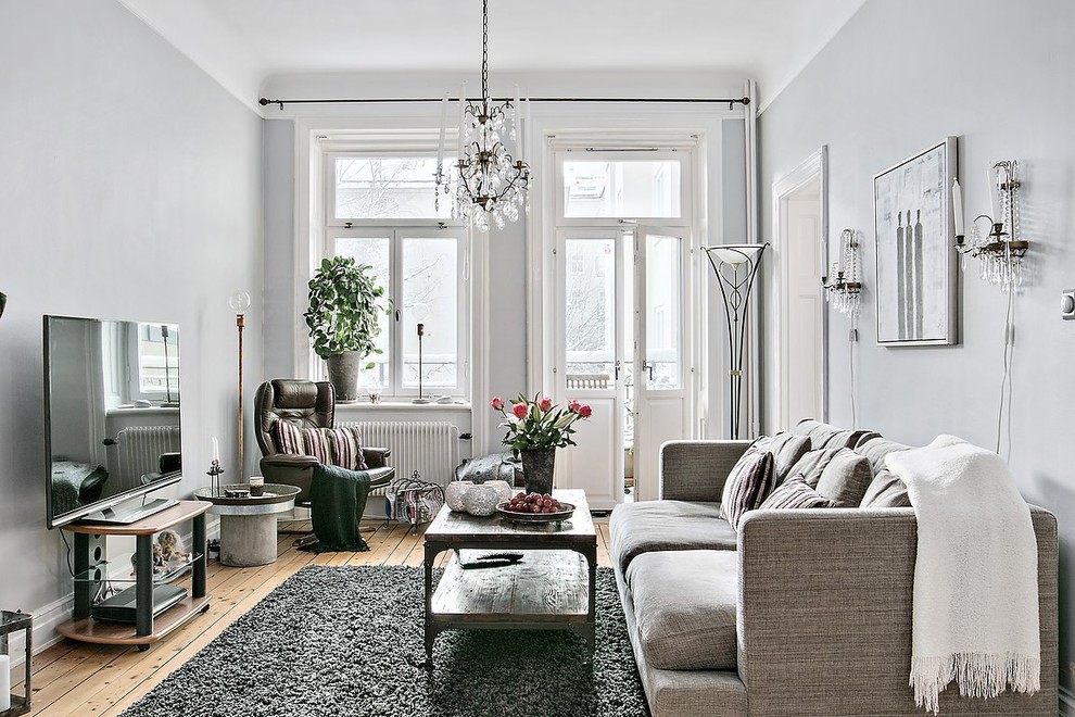 Photo of a medium sized scandi enclosed living room in Stockholm with grey walls, light hardwood flooring and a freestanding tv.