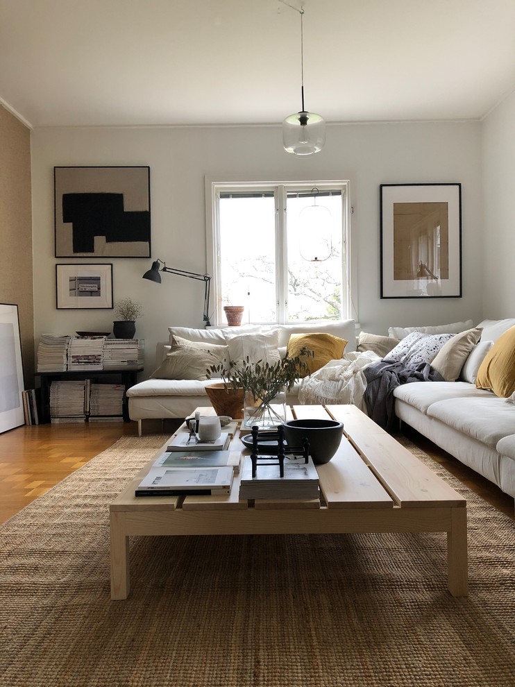 Photo of a scandi enclosed living room in Gothenburg with white walls, medium hardwood flooring and brown floors.