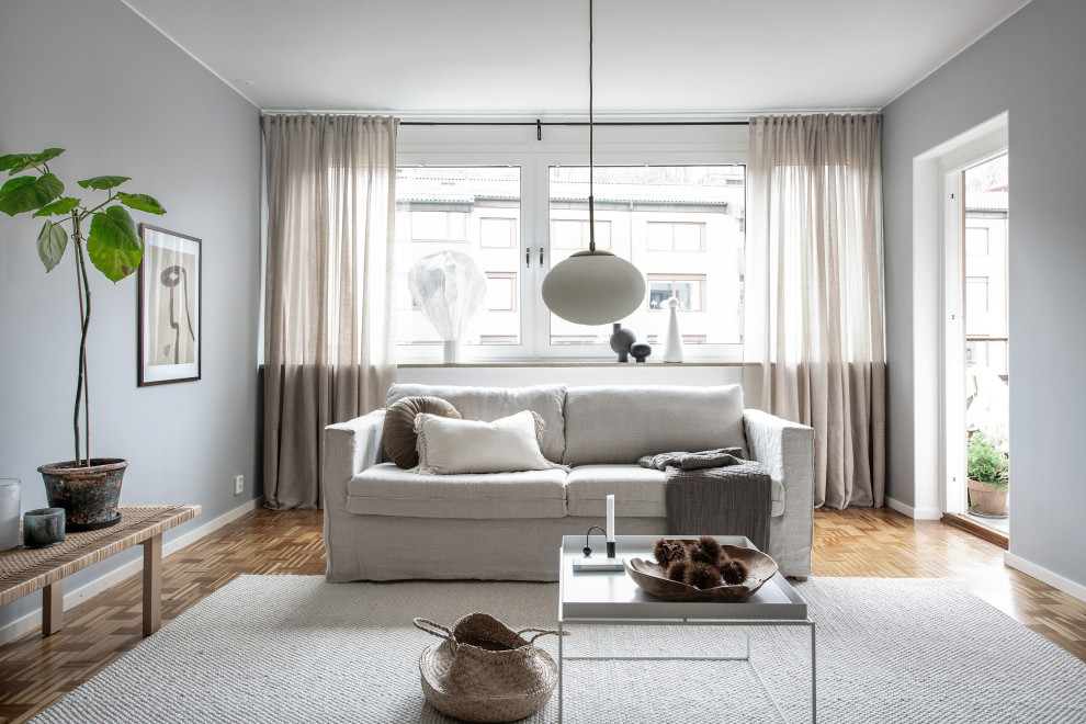 Свежая идея для дизайна: изолированная гостиная комната в скандинавском стиле с серыми стенами, паркетным полом среднего тона и коричневым полом - отличное фото интерьера