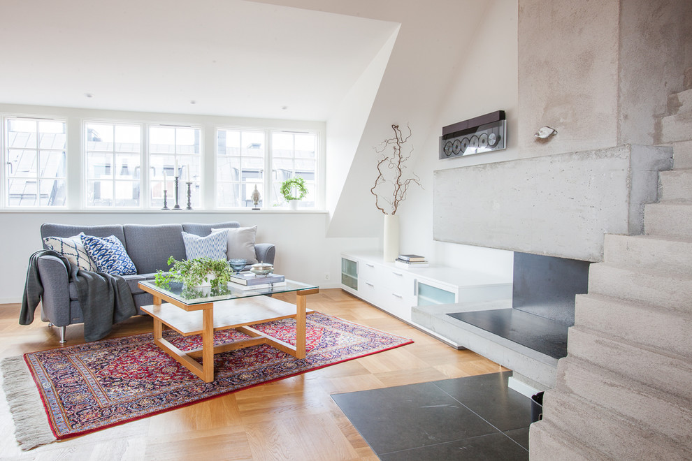 Photo of a medium sized modern formal open plan living room in Stockholm with white walls, a concrete fireplace surround, no tv, medium hardwood flooring and a corner fireplace.