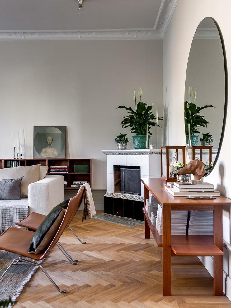Mittelgroßes, Repräsentatives, Fernseherloses, Offenes Nordisches Wohnzimmer mit beiger Wandfarbe, braunem Holzboden und Eckkamin in Stockholm