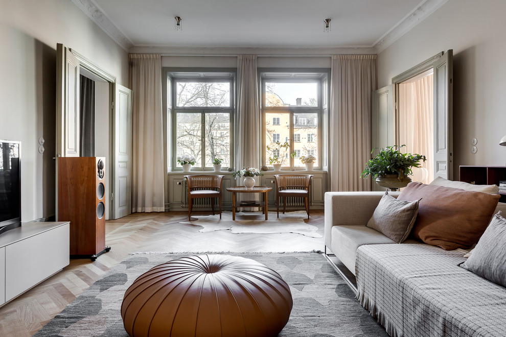 Mittelgroßes Skandinavisches Wohnzimmer mit beiger Wandfarbe, braunem Holzboden und Eckkamin in Stockholm