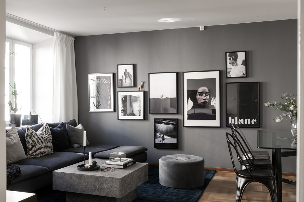 Inredning av ett nordiskt stort vardagsrum, med grå väggar, mellanmörkt trägolv och en väggmonterad TV