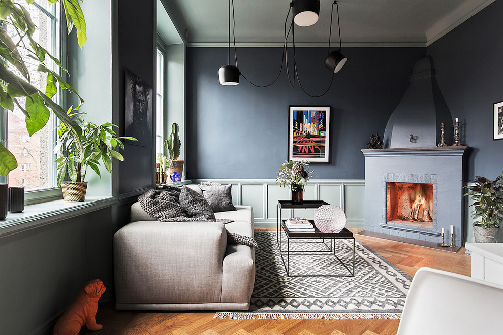 Fernseherloses, Mittelgroßes, Repräsentatives, Offenes Modernes Wohnzimmer mit blauer Wandfarbe, braunem Holzboden und Eckkamin in Stockholm
