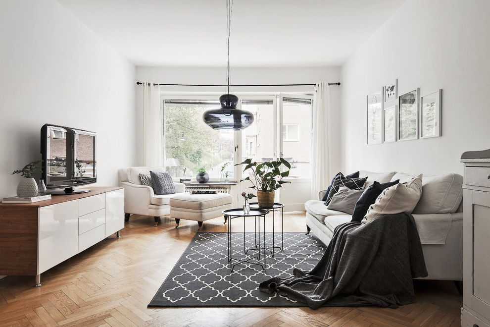 Skandinavisk inredning av ett mellanstort vardagsrum, med vita väggar, ljust trägolv, en fristående TV och ett finrum