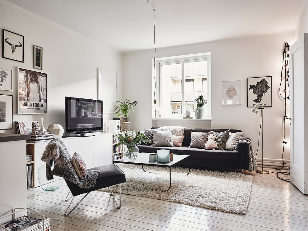 Стильный дизайн: открытая гостиная комната среднего размера в скандинавском стиле с белыми стенами, деревянным полом и отдельно стоящим телевизором без камина - последний тренд