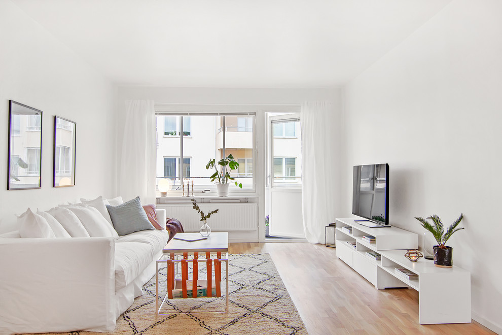 Medium sized scandinavian formal open plan living room in Stockholm with white walls, light hardwood flooring and a freestanding tv.