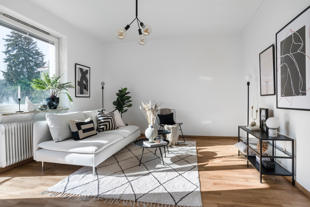 Immagine di un soggiorno scandinavo di medie dimensioni e aperto con sala formale, pareti bianche, pavimento in legno massello medio, nessuna TV e pavimento marrone