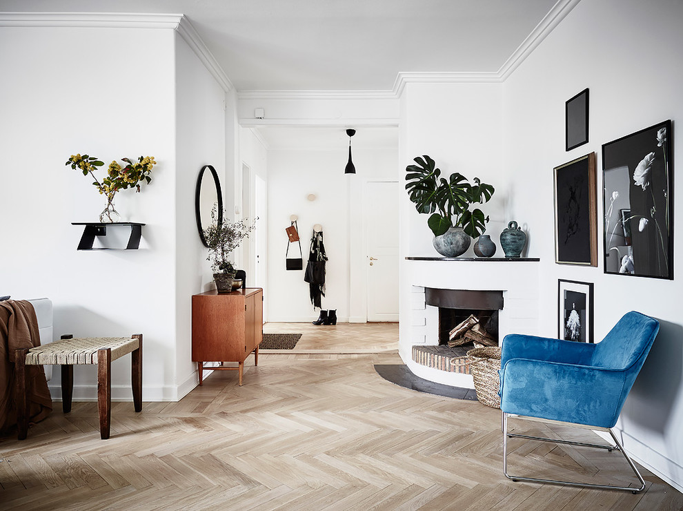 Ejemplo de salón escandinavo con paredes blancas, suelo de madera clara y marco de chimenea de yeso