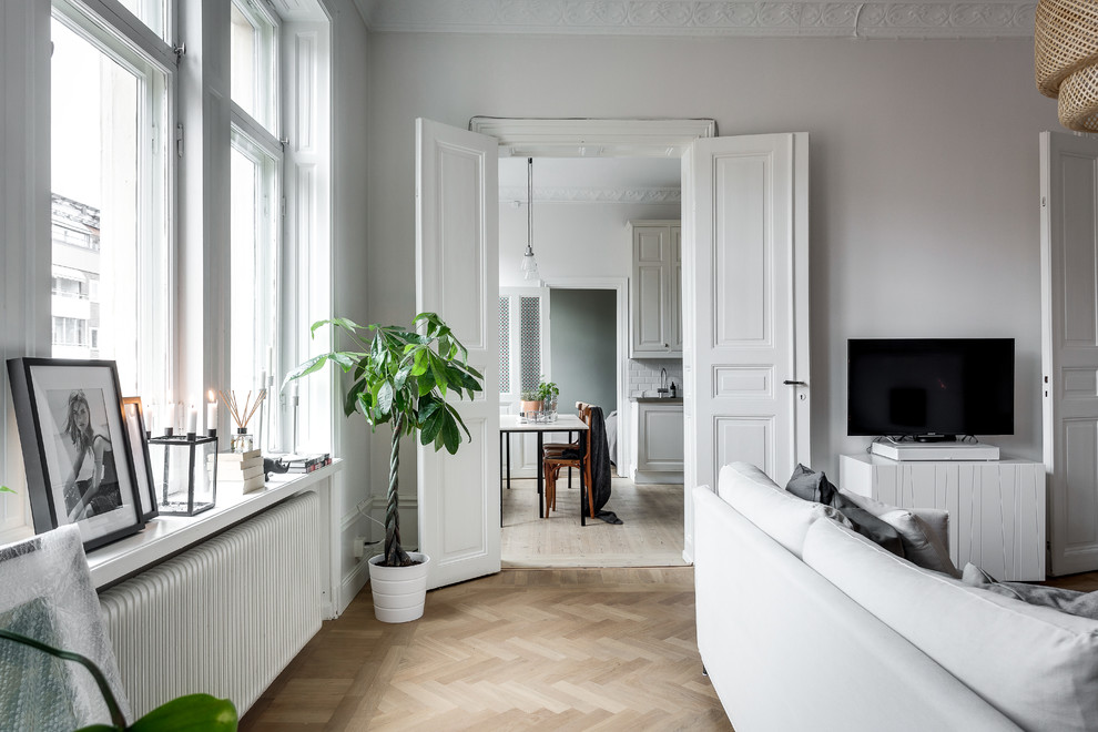 Example of a mid-sized ornate medium tone wood floor living room design in Stockholm with white walls, a corner fireplace and a tv stand