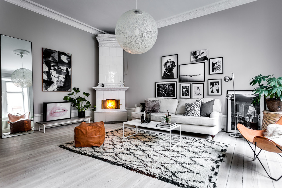 Abgetrenntes, Mittelgroßes, Repräsentatives Skandinavisches Wohnzimmer mit grauer Wandfarbe, gebeiztem Holzboden, Eckkamin und gefliester Kaminumrandung in Stockholm