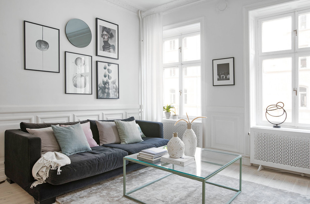 Nordisches Wohnzimmer mit weißer Wandfarbe, gebeiztem Holzboden und weißem Boden in Stockholm