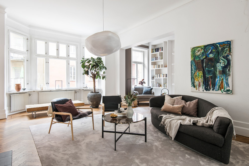 Danish enclosed medium tone wood floor living room photo in Stockholm with white walls