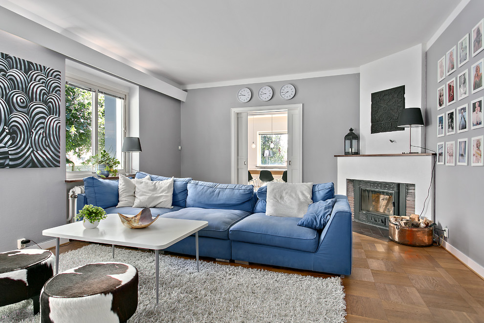 This is an example of a medium sized scandinavian formal enclosed living room in Malmo with grey walls, light hardwood flooring, a corner fireplace, no tv and feature lighting.