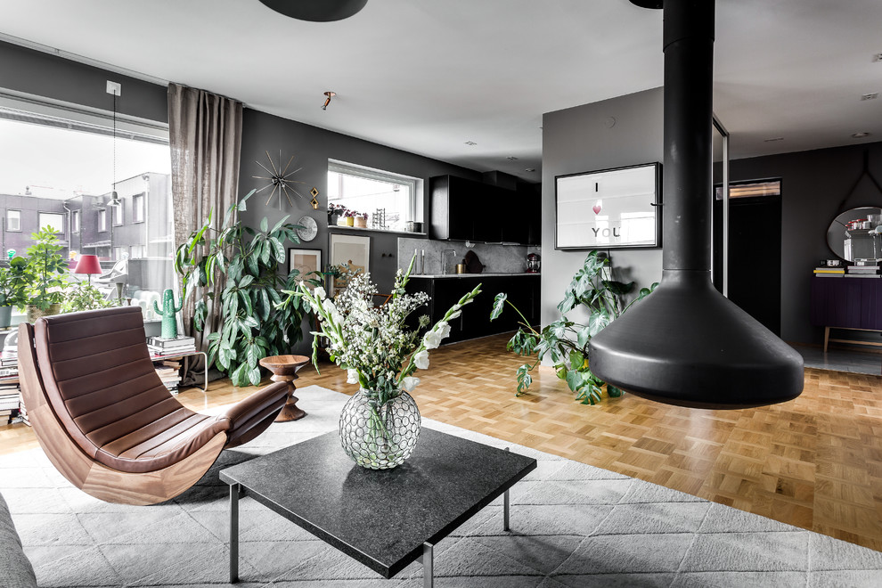 Großes, Offenes, Repräsentatives, Fernseherloses Nordisches Wohnzimmer mit braunem Holzboden, grauer Wandfarbe und Hängekamin in Stockholm