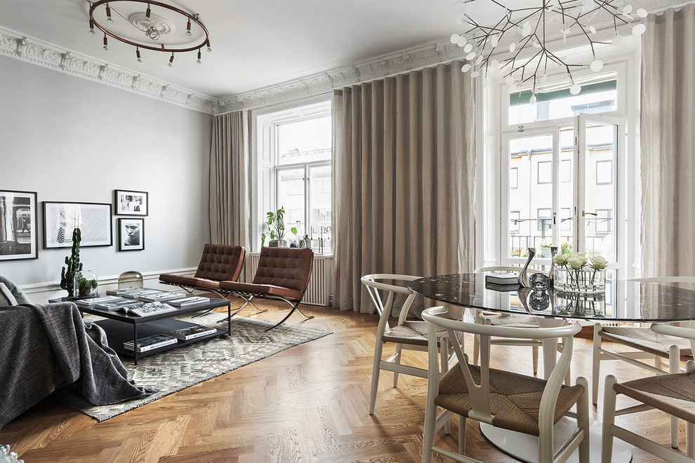 Стильный дизайн: большая парадная, открытая гостиная комната в скандинавском стиле с серыми стенами и паркетным полом среднего тона без камина, телевизора - последний тренд