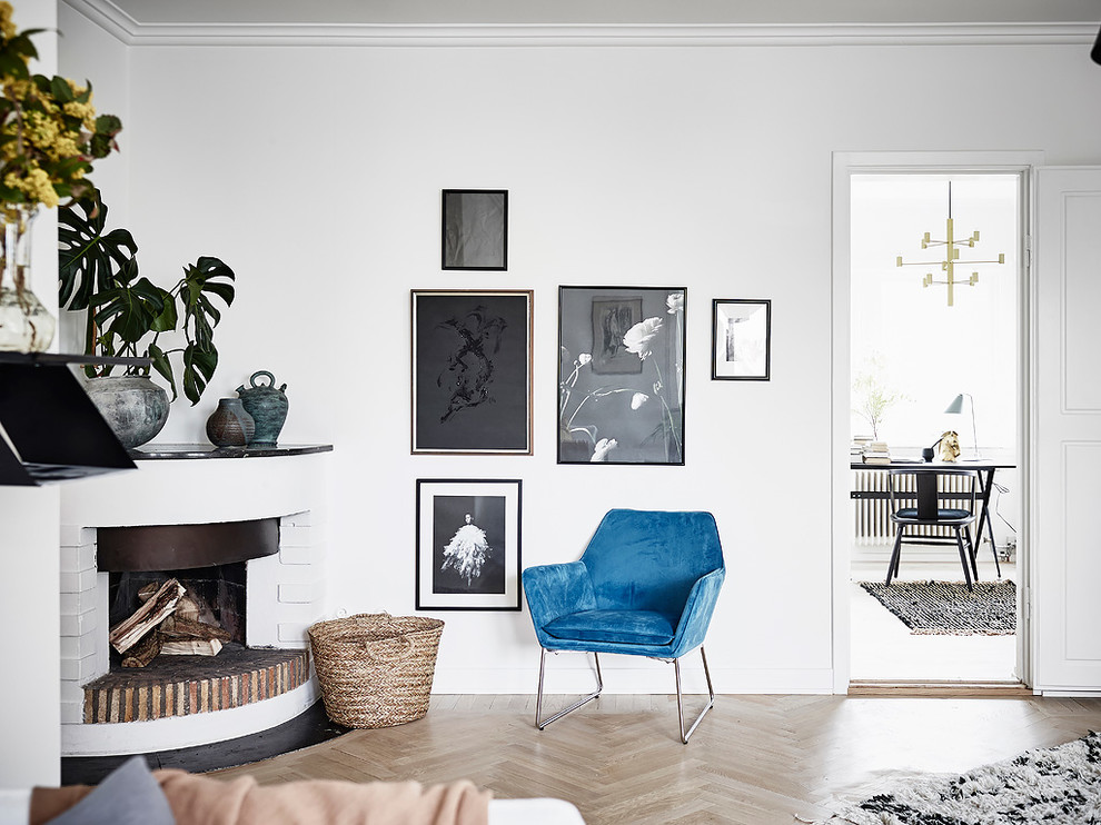 Bild på ett minimalistiskt separat vardagsrum, med vita väggar, ljust trägolv, en öppen vedspis, en spiselkrans i betong och beiget golv