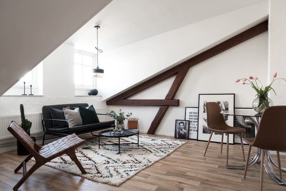 Aménagement d'un salon scandinave ouvert avec un mur blanc, parquet clair, un sol marron et canapé noir.