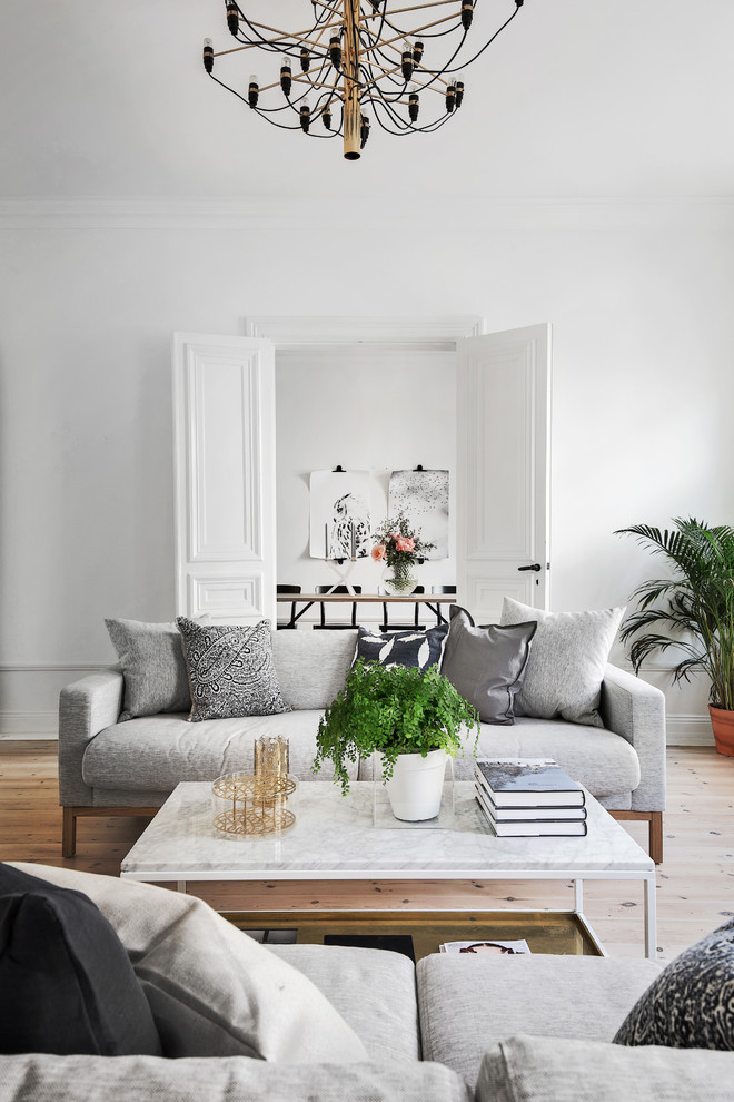 This is an example of a medium sized scandi formal open plan living room in Stockholm with white walls and light hardwood flooring.
