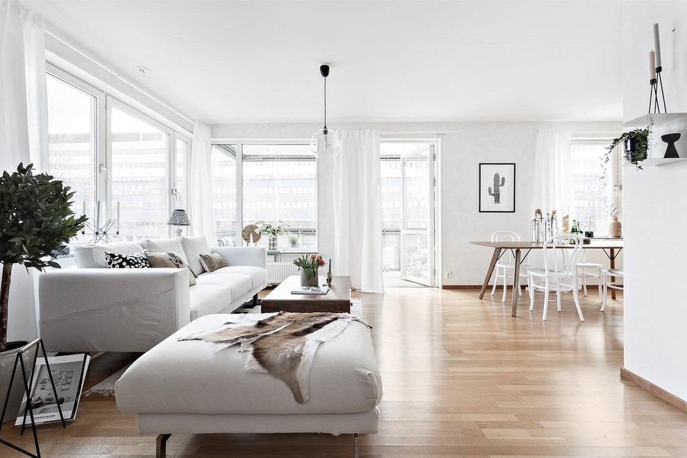 Modelo de salón para visitas abierto escandinavo sin chimenea con paredes blancas, suelo de madera en tonos medios y suelo marrón