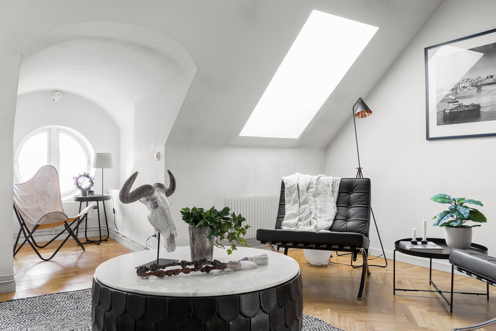 На фото: гостиная комната в скандинавском стиле с белыми стенами и светлым паркетным полом без камина