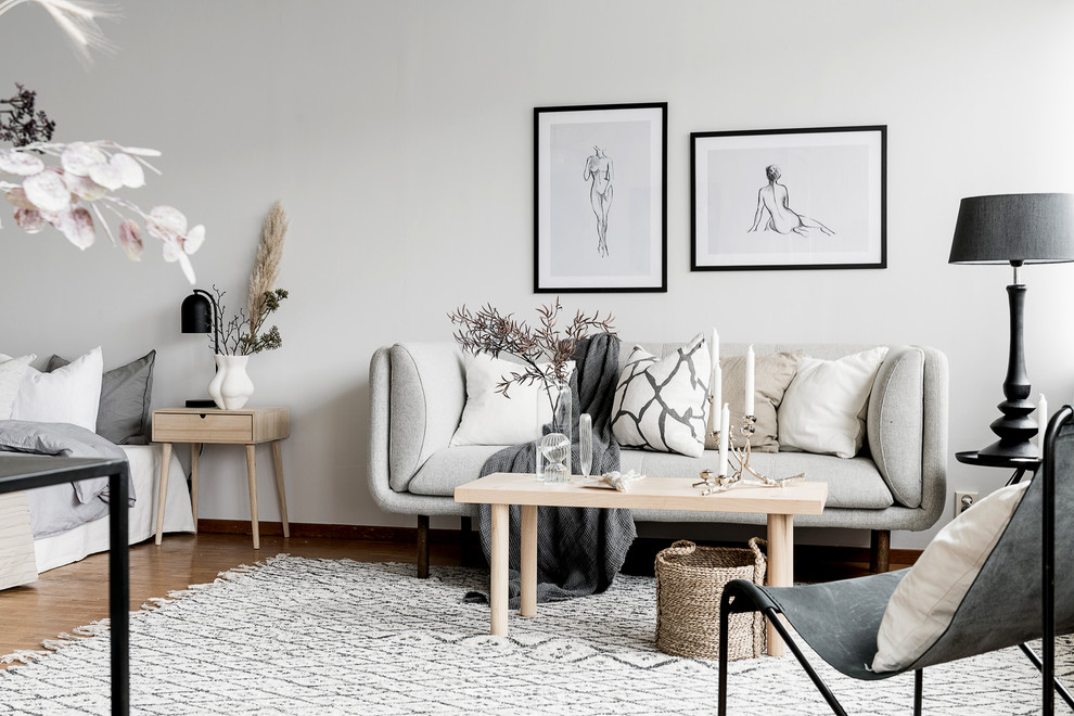 Ejemplo de salón abierto escandinavo pequeño con paredes blancas y suelo de madera en tonos medios