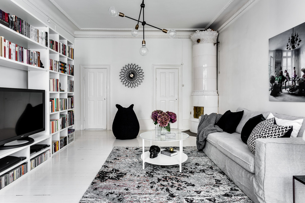 Mittelgroßes, Offenes Klassisches Wohnzimmer mit grauer Wandfarbe, gebeiztem Holzboden, Eckkamin, gefliester Kaminumrandung und freistehendem TV in Stockholm