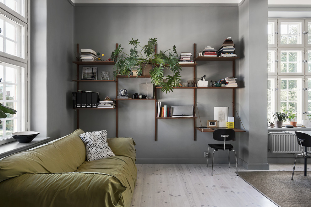 Ejemplo de biblioteca en casa abierta escandinava de tamaño medio sin televisor con paredes grises y suelo de madera clara