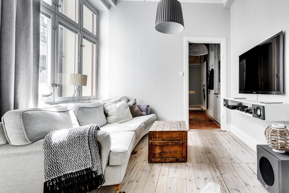 Mid-sized danish open concept light wood floor living room photo in Stockholm with white walls and a wall-mounted tv