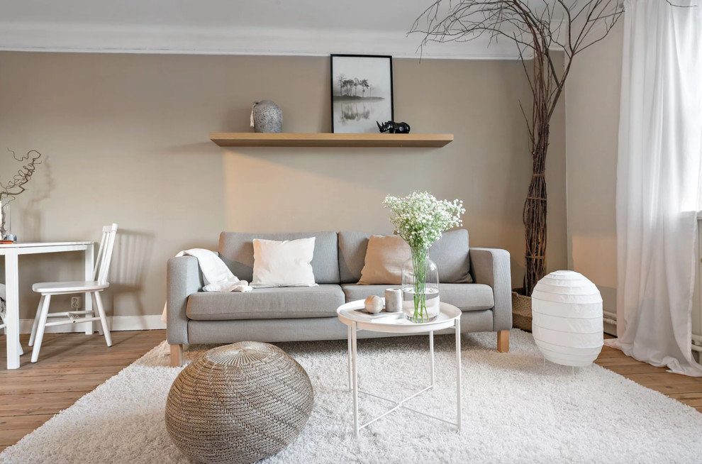 Example of a small danish open concept light wood floor and beige floor living room design in Stockholm with beige walls