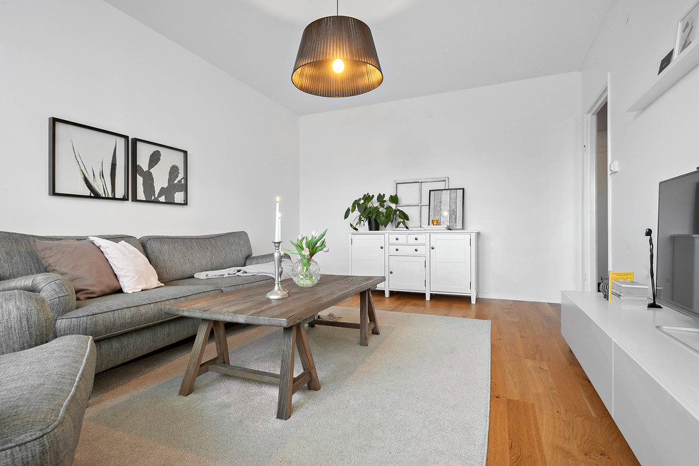 Idee per un soggiorno classico di medie dimensioni e chiuso con pareti bianche, pavimento in legno massello medio, TV autoportante e pavimento beige