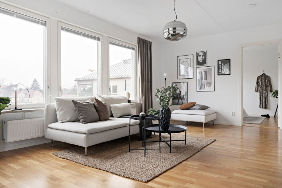 Источник вдохновения для домашнего уюта: открытая гостиная комната среднего размера в скандинавском стиле с белыми стенами, паркетным полом среднего тона и бежевым полом