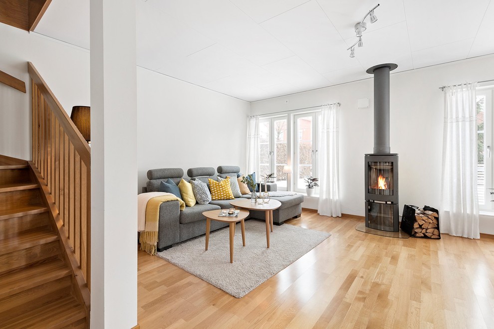 Immagine di un soggiorno minimal con sala formale, pareti bianche, pavimento in legno massello medio, stufa a legna, nessuna TV e pavimento marrone