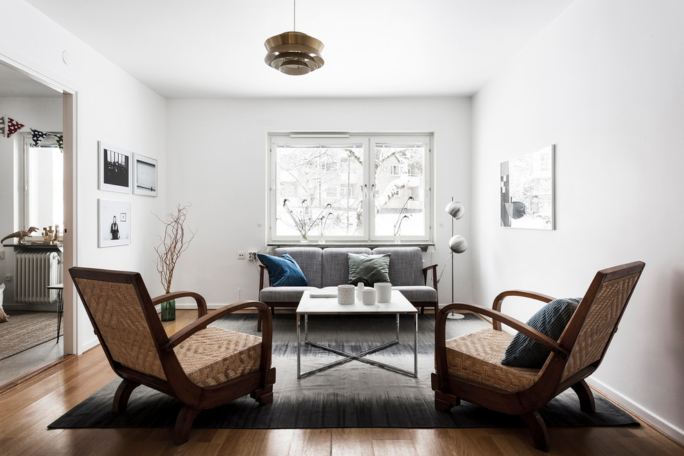 Example of a mid-sized danish medium tone wood floor living room design in Stockholm with white walls, no fireplace and no tv