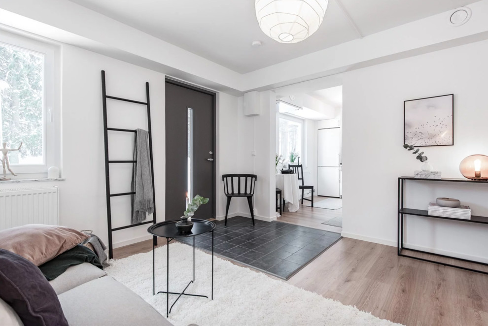 Small scandi open plan living room in Stockholm with white walls, light hardwood flooring and beige floors.