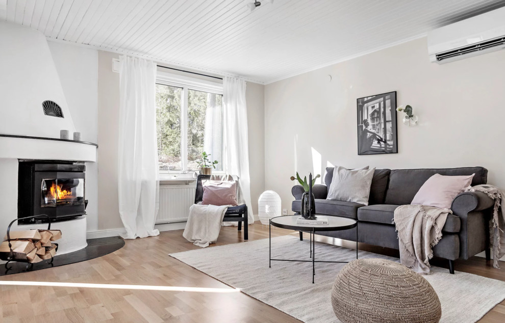 Medium sized scandinavian enclosed living room in Stockholm with beige walls, light hardwood flooring, a corner fireplace, a stone fireplace surround and beige floors.