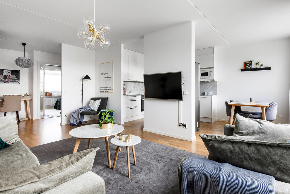Inredning av ett minimalistiskt vardagsrum, med vita väggar, mellanmörkt trägolv, en väggmonterad TV och brunt golv